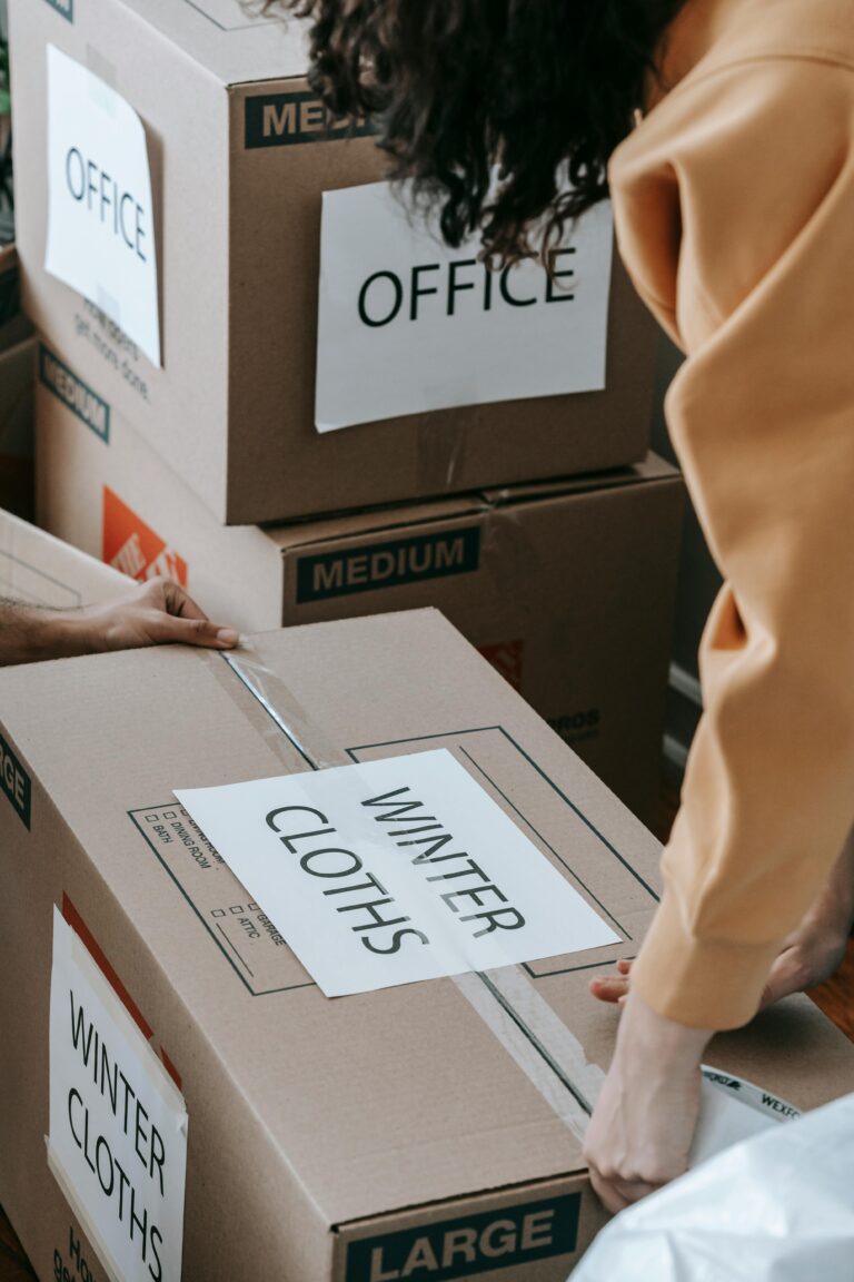 Close-up of people packing labeled boxes for moving day at home.