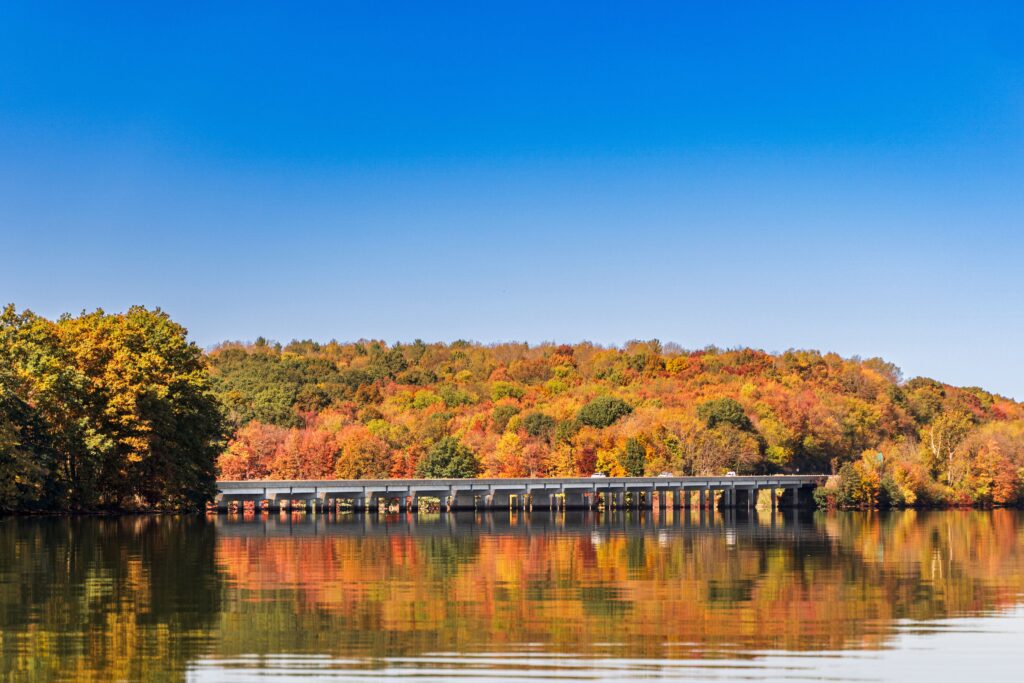 Scenic autumn view of a bridge reflecting over a calm lake in Portersville, Pennsylvania.