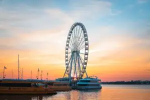 A stunning sunset view of the iconic Ferris wheel and water taxis at National Harbor in Fort Washington, MD.